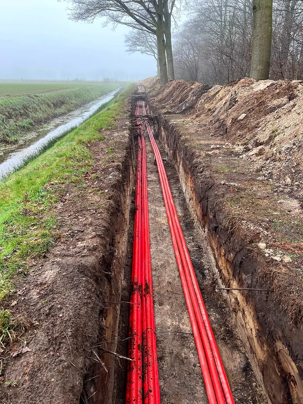 Kabeltracé langs een sloot in de mist