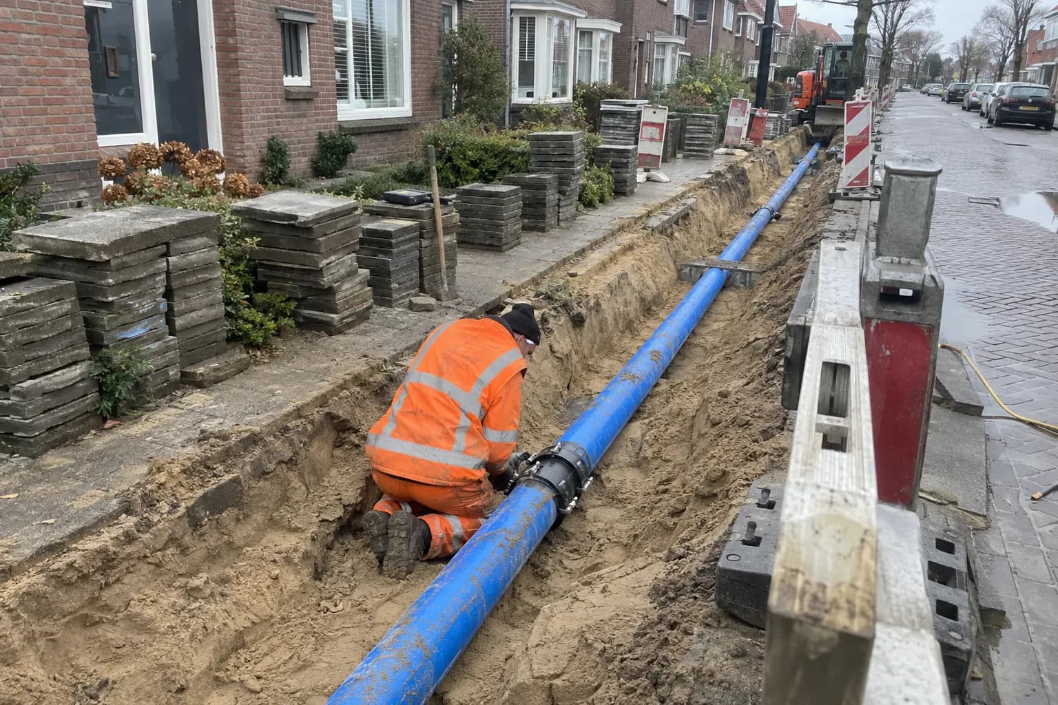 Blauwe waterleiding in een open sleuf, klaar om aangevuld te worden met zand